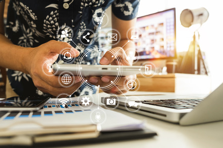Man using smart phone for mobile payments online shopping,omni channel,sitting on table,virtual icons graphics interface screen in morning lightの写真素材
