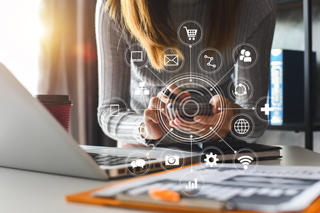 businesswoman or Designer using mobile phone with laptop and digital tablet laptop and document on desk in office with virtual icons network diagram in morning lightの写真素材