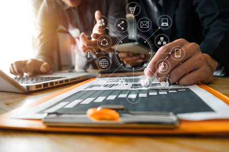 Business documents on office table with smart phone and calculator digital tablet and graph business with social network diagram and two colleagues discussing data working in the officeの写真素材