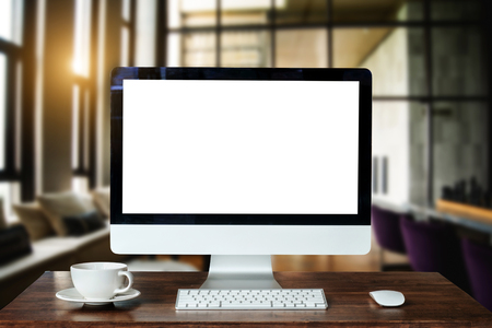 Workspace with computer Monitor, Keyboard, blank screen coffee cup smartphone, and tablet on a table or White Screen Isolated in bright office room interior.の写真素材