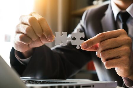 Business solutions and success concept. Businessman hand connecting jigsaw puzzle.の写真素材