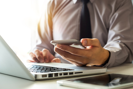 businessman hand using smart phone, tablet payments and holding credit card online shopping, omni channel, digital tablet docking keyboard computer at office in sun lightの写真素材