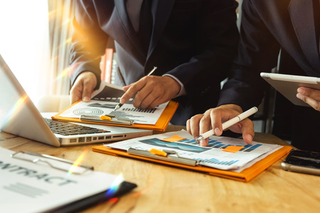 Business documents on office table with smart phone and calculator digital tablet and graph business with social network diagram and two colleagues discussing data working in the officeの写真素材
