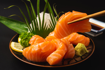 Sashimi, Salmon, Japanese food chopsticks and wasabi on the black tableの写真素材