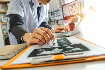 Medical technology concept. Doctor working with mobile phone and stethoscope and digital tablet laptop in modern office at hospital in morning lightの写真素材