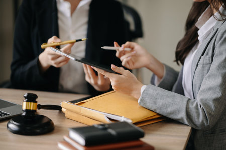 Asian Business and lawyers discussing contract papers with brass scale on desk in office. Law, legal...