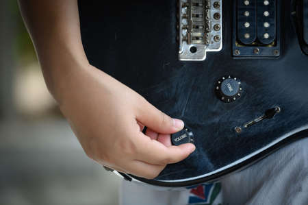woman hand changing electric guitar settings. Tuning a timbre regulator