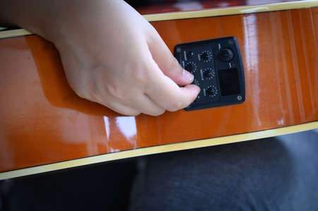 woman's hand holding of an acoustic guitar equalizer.