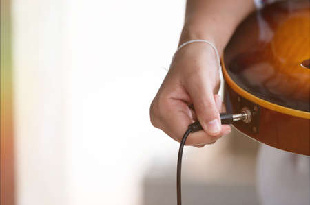 Plug jack cable in electric guitar,Hand inserts input jack to electric guitarの写真素材