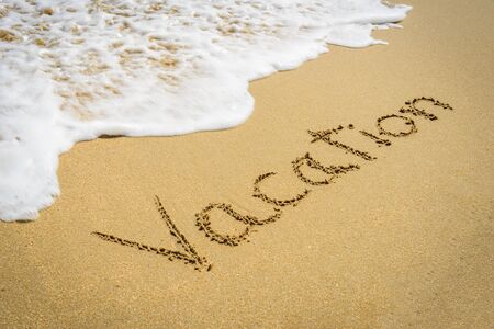 Word vacation on the beach sand - vacation and travel conceptの写真素材
