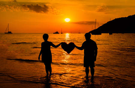 Silhouette of a couple on the beach at sunsetの写真素材
