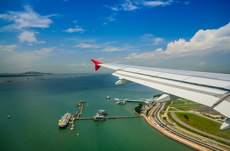 Wing of airplane flying above sea and jetty.の写真素材