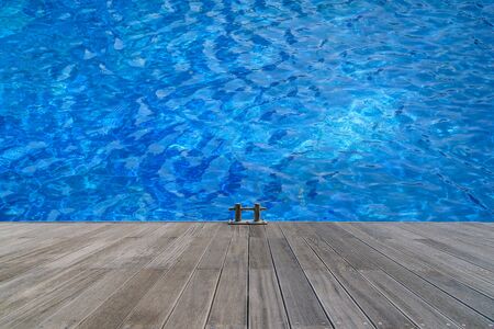 Photo of Water in a swimming pool with sunny reflections and wooden walkway.