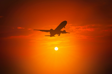 Silhouette of plane fly on sky during sunset.の写真素材
