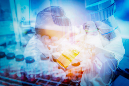 Test tube in scientist hand and Female scientist doing a test in a biological laboratory. Double...