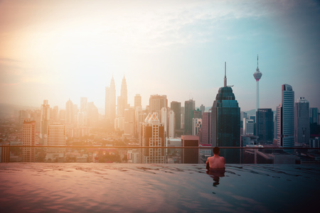 Traveler man in swimming pool on the roof top of hotel at sunrise in Kuala Lumpur, Malaysia. Vintage toneのeditorial素材
