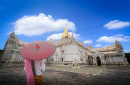 Woman Myanmar holding traditional red umbrella on the Ananda temple at daytime in Bagan, Myanmar.の写真素材