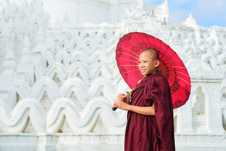 MANDALAY, MYANMAR, -DECEMBER 11, 2017 : Unidentified Asian young monk holding red umbrellas on the Mya Thein Tan Pagoda at Mingun, Mandalay Myanmar.のeditorial素材