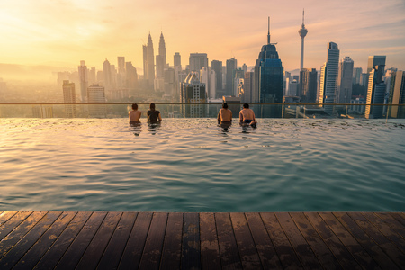 Traveler looking view skyline Kuala Lumpur city in swimming pool on the roof top of hotel at sunrise in Kuala Lumpur, Malaysia.の写真素材