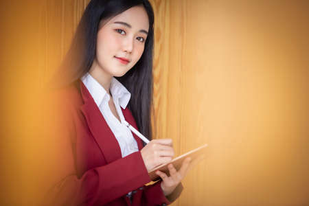 Portrait of Young asian businesswoman sitting indoors in cafe drinking coffee using smart phone....