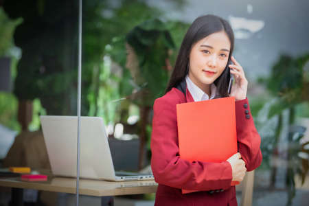 Portrait of Young asian businesswoman sitting indoors in cafe drinking coffee using smart phone....