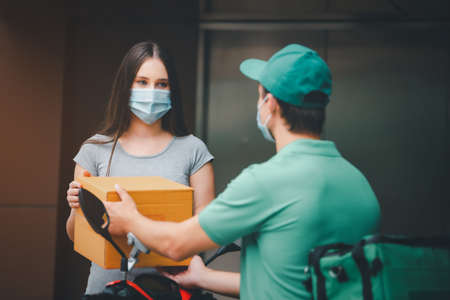 Delivery man employee in green cap t-shirt ready to send delivery food box in front of custom office. Delivery and shopping online concept.の写真素材