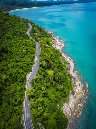 Aerial view of road between coconut palm tree and great ocean at daytime in Nakhon Si Thammarat,...