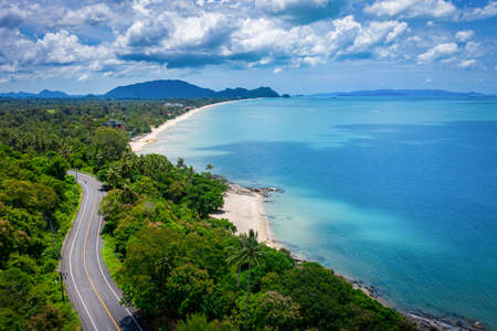 Aerial view of road between coconut palm tree and great ocean at daytime in Nakhon Si Thammarat, Thailandの写真素材