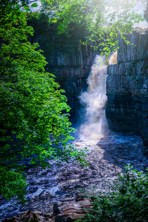 High Force Waterfall views from the south bank of the River Tees on the Pennine Way in woodland, UK.