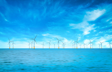 Offshore Wind Turbine in a Windfarm under construction off the England Coast at blue sky