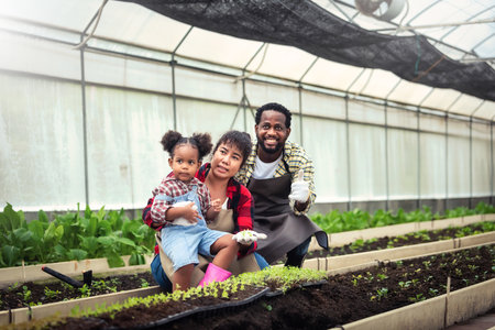 Portrait of African man and wife teaching the children to plant seedlings in greenhouseの写真素材