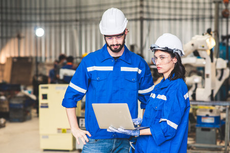 Engineers team mechanic using computer controller Robotic arm for welding steel in steel factory...