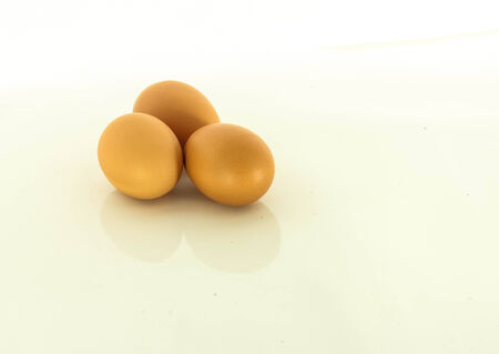 Three chicken eggs lay on a white background.の写真素材