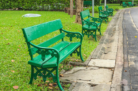 Green the bench placed along the road in the park.の写真素材