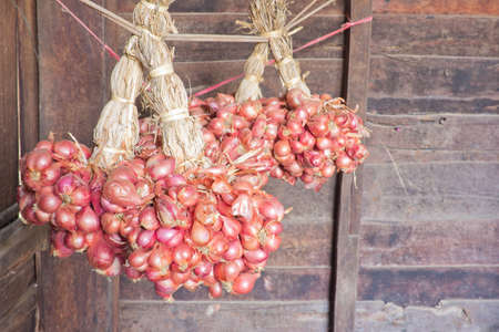 Red onions hanging on a rope in the house.の写真素材