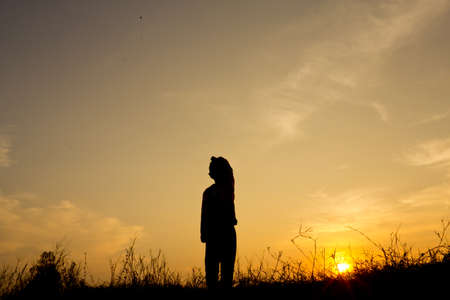 Silhouette of a boy playing a kite in a field on the morning of rural Thailand.の写真素材