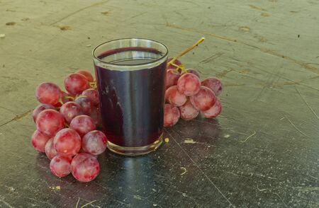 Grape juice is placed on a plank floor.の写真素材