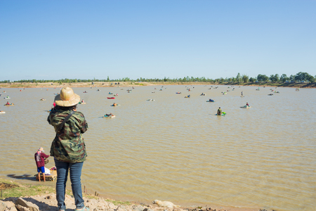 BURIRAM, THAILAND - DECAMBER 10, 2018: Women standing watching people catching fish in the swamps at Na Pho district. Of Buriram Provinceのeditorial素材