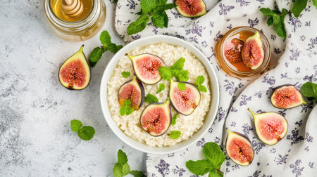 Flat-lay arrangement of breakfast essentials semolina porridge, figs, a jar of honey, fresh mint, and a floral linen napkinの素材