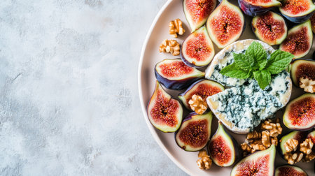 A platter featuring creamy Gorgonzola picante blue cheese, fresh figs, walnuts, and a sprig of mint, styled on a soft pastel surfaceの素材