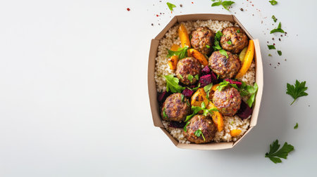 Flat lay of an eco-friendly takeaway box filled with vegan meatballs, beetroot hummus, couscous, and crunchy vegetables, isolated on a white background.の素材