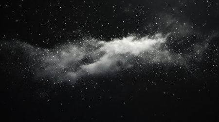 A sudden dust cloud disperses explosively, with tiny particles catching the light on a black background.の素材