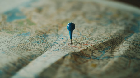 Travel planning concept with a blue push-pin stuck in a paper map, zoomed-in details of roads, highways, and cities, selective focusの素材