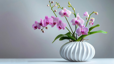 Stylish vase with a unique shape and texture, holding a fresh bouquet of purple orchids and green stemsの素材