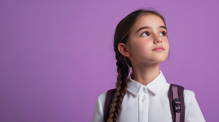 Thoughtful Latin girl in school uniform, standing with a backpack, gazing away with a dreamy expression. Great for educational themes. Lilac violet background.の素材
