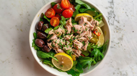 Top view of a tuna salad with mixed greens, cherry tomatoes, olives, and a lemon vinaigrette.の素材