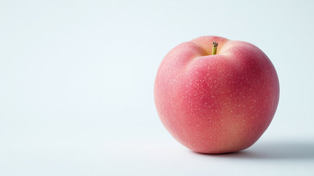 A single, fresh Japanese peach with its vibrant skin, isolated on a clean white background. Copy space provided.の素材