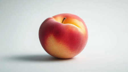 Close-up of a single Japanese peach, with its delicate skin on display, isolated on a clean white surface.の素材