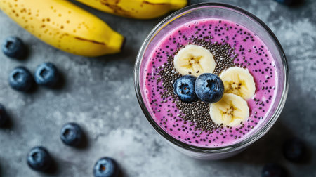 A healthy blueberry and banana smoothie with chia seeds and yogurt, served in a glass on a gray concrete surface.の素材