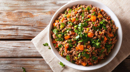 A white bowl filled with a savory mix of minced beef and vegetables, garnished with parsley, placed on a rustic tablecloth, fresh and wholesome meal, top viewの素材